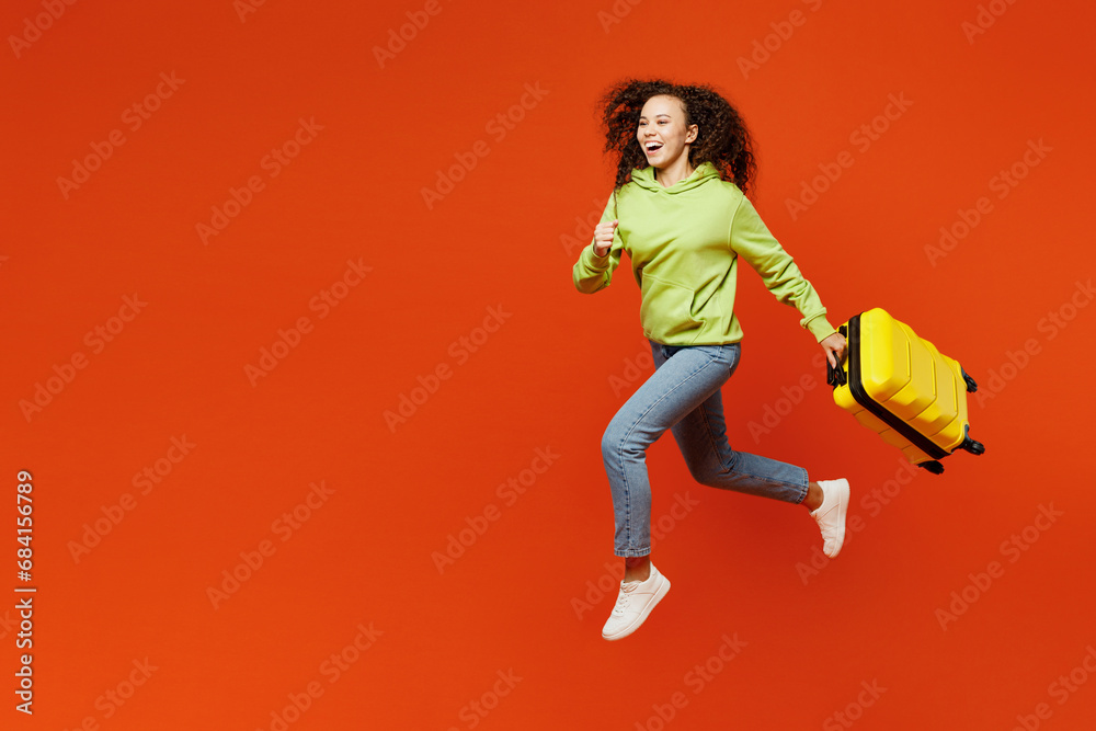 Side view traveler excited woman wear casual clothes run hold suitcase bag isolated on plain orange background. Tourist travel abroad in free spare time rest getaway. Air flight trip journey concept. Side view traveler excited woman wear casual clothes run hold suitcase bag isolated on plain orange background. Tourist travel abroad in free spare time rest getaway. Air flight trip journey concept.