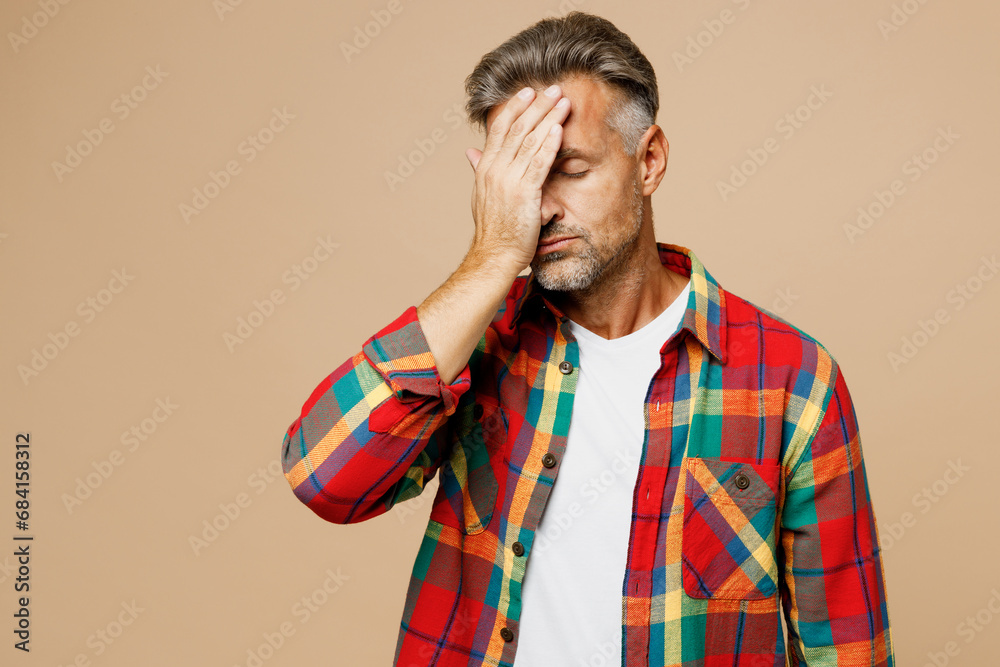 Adult sad man he wear red shirt white t-shirt casual clothes put hand on face facepalm epic fail mistaken omg gesture isolated on plain pastel light beige color background studio. Lifestyle concept. Adult sad man he wear red shirt white t-shirt casual clothes put hand on face facepalm epic fail mistaken omg gesture isolated on plain pastel light beige color background studio. Lifestyle concept.