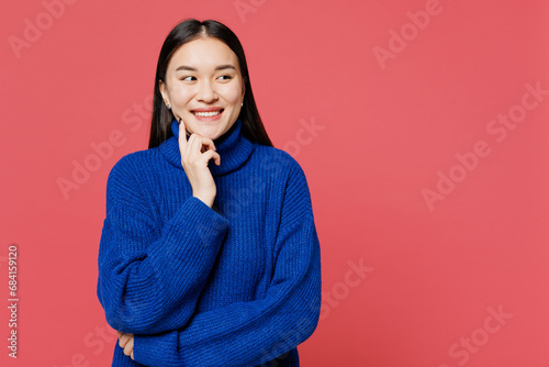 Young woman of Asian ethnicity wear blue sweater casual clothes put hand prop up on chin, lost in thought and conjectures isolated on plain pastel pink background studio portrait. Lifestyle concept.