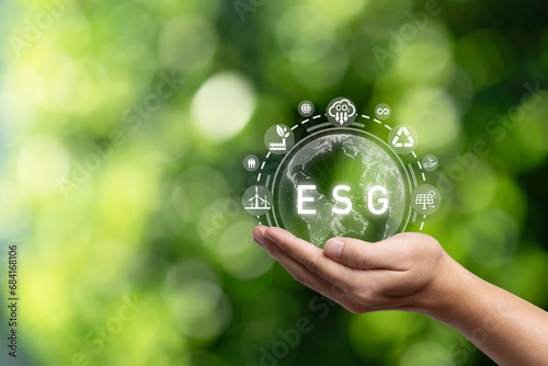 Hand holding virtual world with environmental icon on green background for Environment Social Governance to sustainable development in business and ecology concept.
