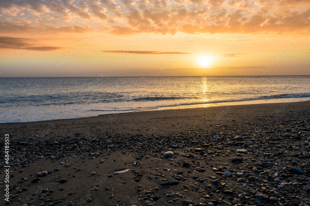 morning landscape with coast on foreground, sand of a beach, blue sea with surf and waves and cloudy sunset or sunrise on background morning landscape with coast on foreground, sand of a beach, blue sea with surf and waves and cloudy sunset or sunrise on background