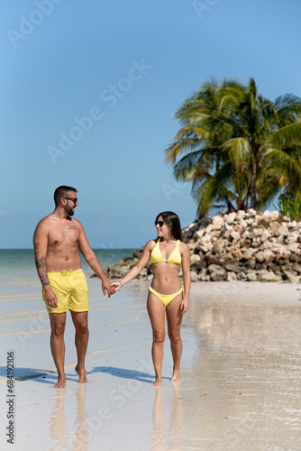 Young couple on vacation walking on the beach with no one around, surrounded by palm trees in Holbox, Mexico.