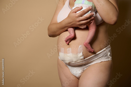 Cropped view of woman mother standing together with her newborn baby. Real body of women after few days of childbirth. photo