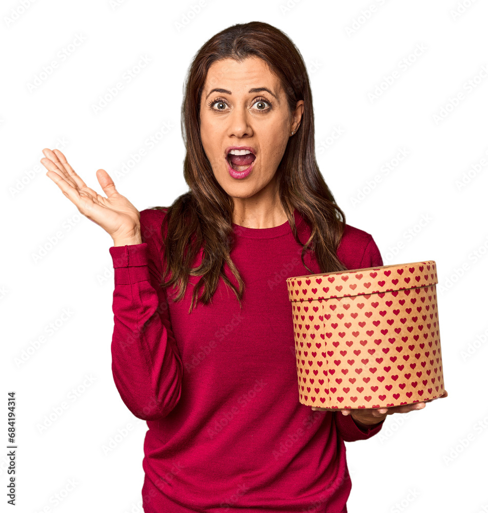 Middle-aged woman with Valentine's Day heart box in studio surprised and shocked. Middle-aged woman with Valentine's Day heart box in studio surprised and shocked.