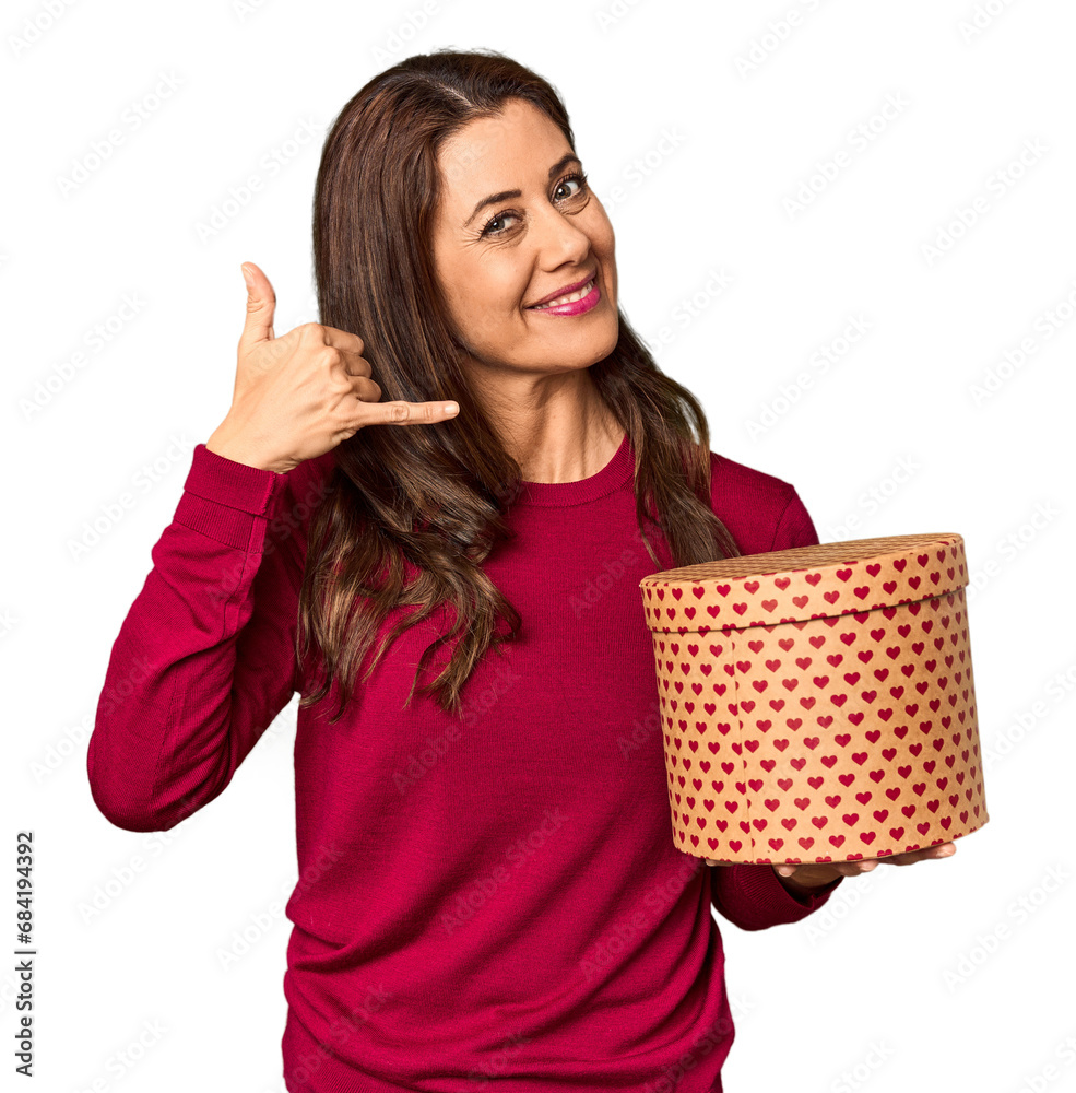 Middle-aged woman with Valentine's Day heart box in studio showing a mobile phone call gesture with fingers. Middle-aged woman with Valentine's Day heart box in studio showing a mobile phone call gesture with fingers.