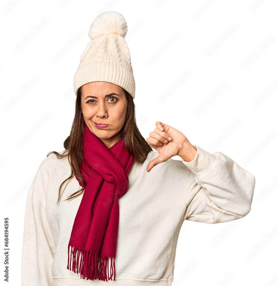 Middle-aged woman in cozy Christmas winter wear in studio showing a dislike gesture, thumbs down. Disagreement concept. Middle-aged woman in cozy Christmas winter wear in studio showing a dislike gesture, thumbs down. Disagreement concept.