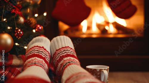 Feet in woollen socks by the Christmas fireplace with space for text photo