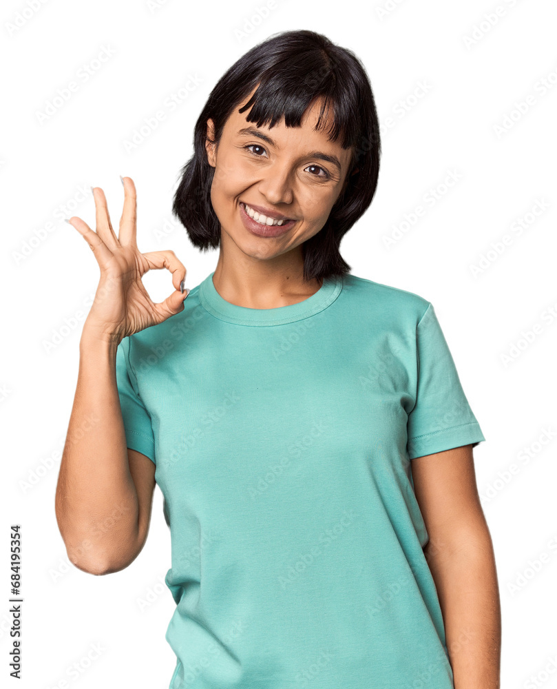 Young Hispanic woman with short black hair in studio winks an eye and holds an okay gesture with hand. Young Hispanic woman with short black hair in studio winks an eye and holds an okay gesture with hand.