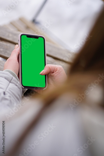 Girl using blank smartphone screen without frame - back view over shoulder photo