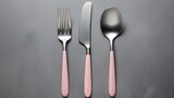 Silver fork, knife and spoons with pink handle on grey background, copy space, 16:9