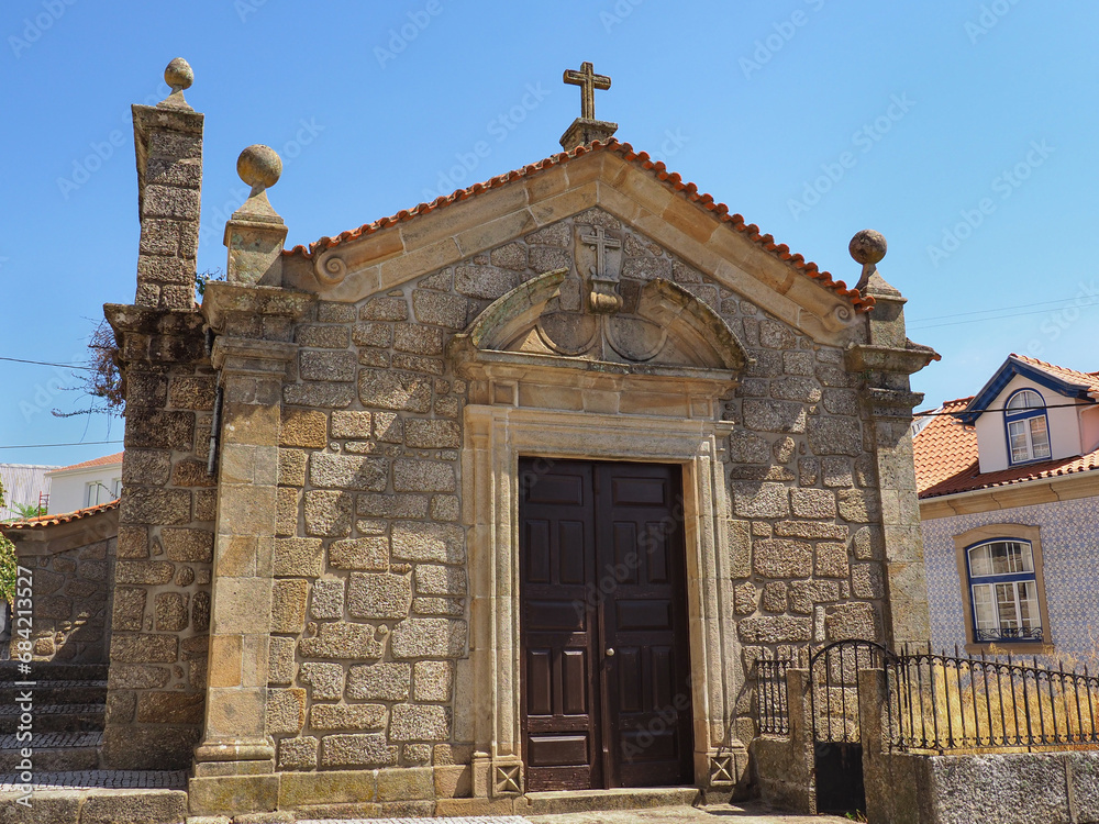 Small catholic Church or Capela de São Silvestre, Covilha, Portugal. Beautiful facade of a stone masonry mannerist chapel with wooden door, cross and bell tower.