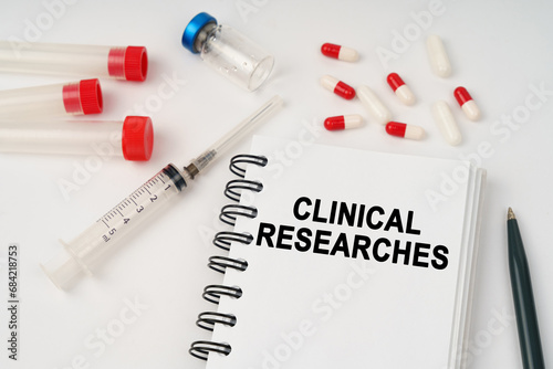 On the table are pills, injections, a syringe and a notepad with the inscription - clinical researches