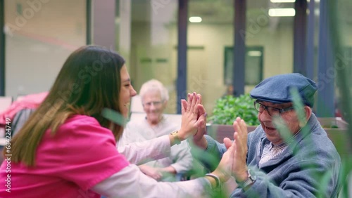 Nurse and old man high five in a nursing home photo