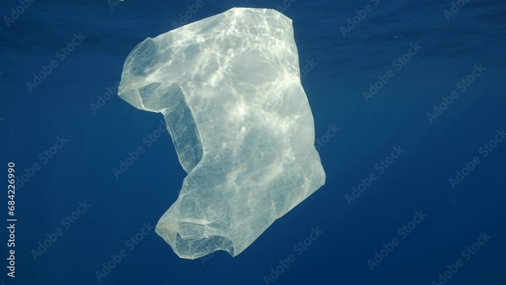 Close uo of discarded disposable white plastic bag slowly swims under waves of Mediterranean sea in bright sunbeams, Slow motion. Plastic pollution of Ocean Close uo of discarded disposable white plastic bag slowly swims under waves of Mediterranean sea in bright sunbeams, Slow motion. Plastic pollution of Ocean