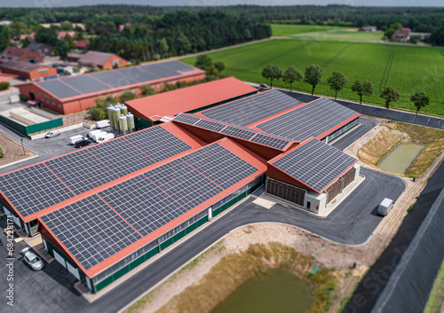 Moderne Tierhaltungsst  lle mit gro  fl  chig auf den D  chern montierte Photovoltaikanlagen zur nachhaltigen Energieerzeugung. Luftbild - Symbolfoto.