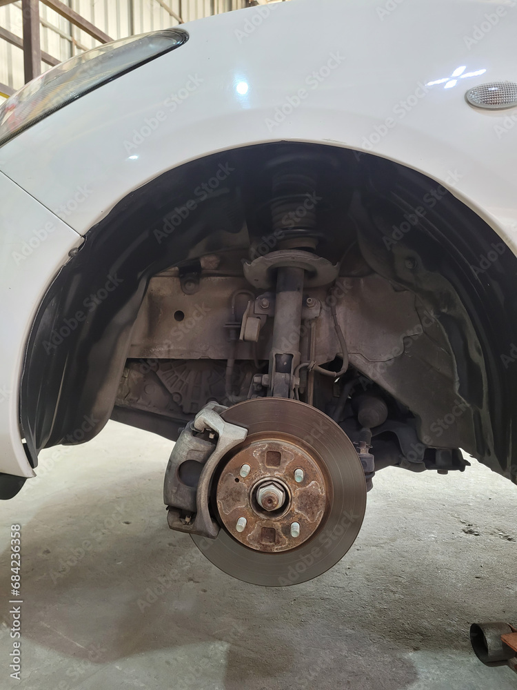 Disc brake of the vehicle for repair at garage, in process of new tire replacement, Suspension of car for maintenance brakes and shock absorber systems.