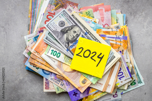 2024 in finance, Business concept, Big pile of money, All world currencies and yellow sticky note with the year 2024, World economic situation, armed conflicts, currency markets