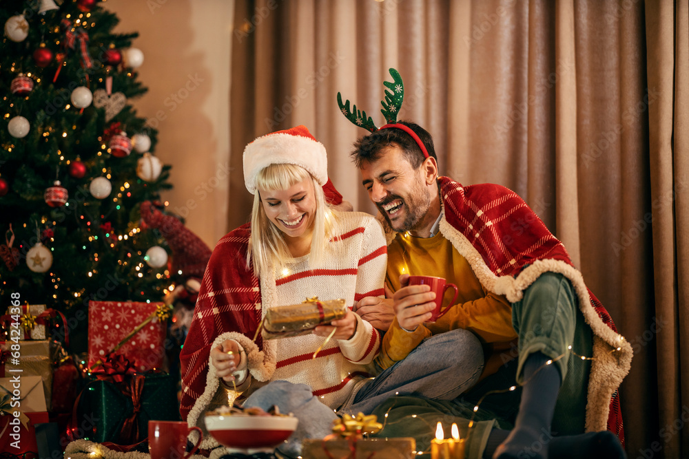 A jolly couple is opening christmas gift and having fun at home on christmas and new year's eve.