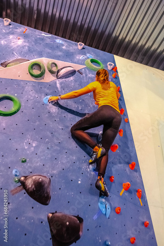 Young woman climbing on a climbing wall in a gym