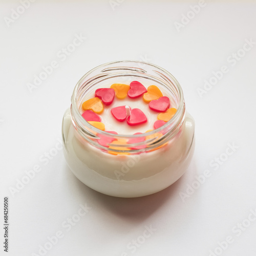 A candle in a glass jar with a composition of hearts.