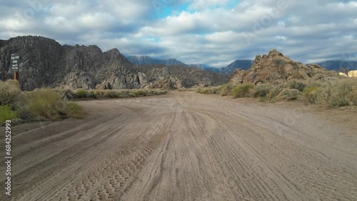 Drone footage of Alabama Hills in California following Movie Road dirt track and then panning upwards to see wider landscape.