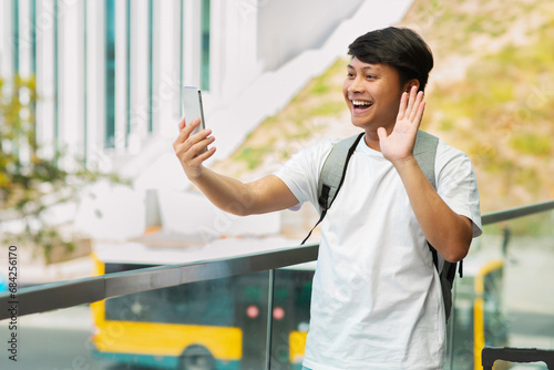 Positive asian guy travel blogger taking selfie by phone photo