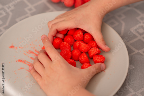 Child's playtime delight tiny hands reaching for red fruity candies on a plate, a sweet symphony of flavors begins