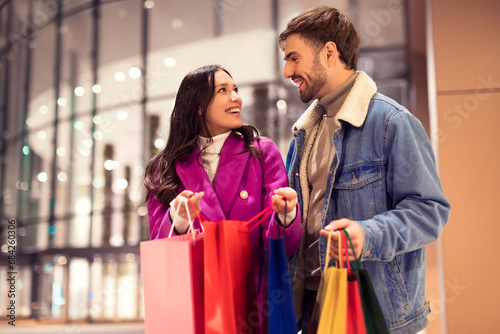 buyers couple in winter attire showing Xmas shopping finds outdoor