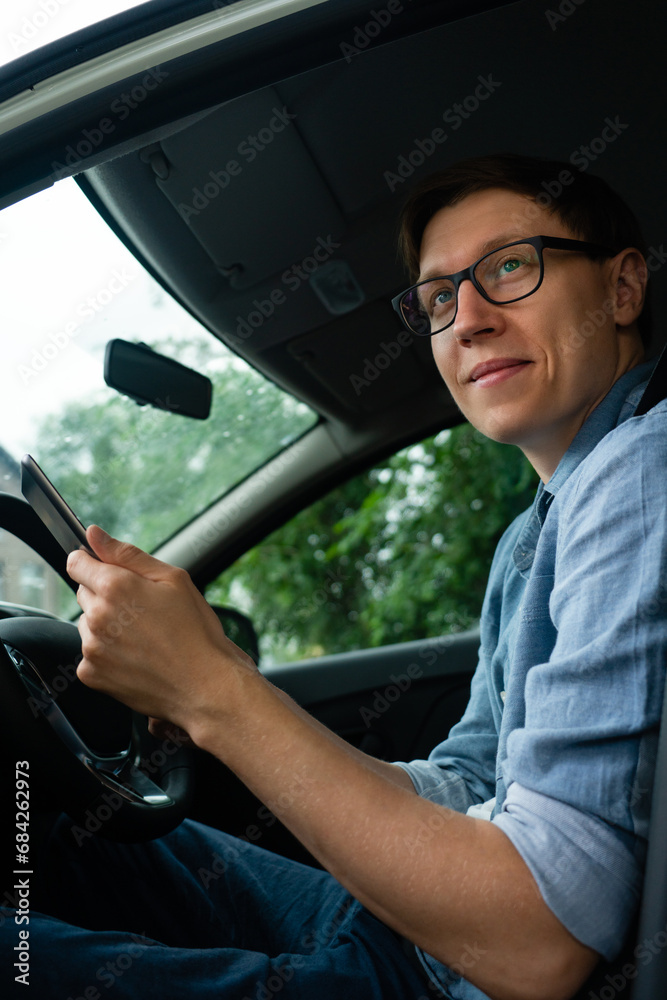 Courier sitting in a car and looking at a digital tablet