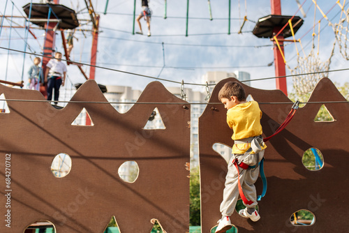 A happy child, a healthy boy is enjoying a summer day in a climbing adventure park. Overcoming obstacles