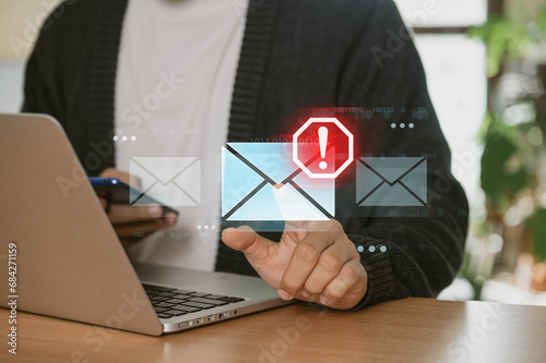 A businessman using a laptop at home is receiving email warning alerts about spam, viruses, and hackers, as well as network security concepts