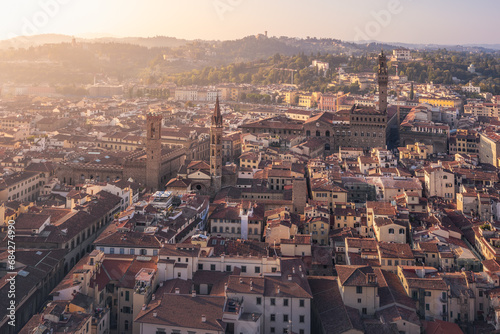Old city with high towers on palaces, tiled roofs and hills in golden morning haze, Florence, Italy
