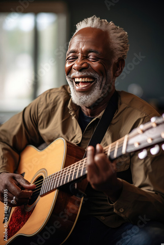 Joyful senior African American man playing the guitar with laughter and enjoyment suitable for music industry and hobby-related themes