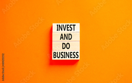 Invest and do business symbol. Concept word Invest and do business on beautiful wooden block. Beautiful orange table orange background. Invest and do business concept. Copy space.