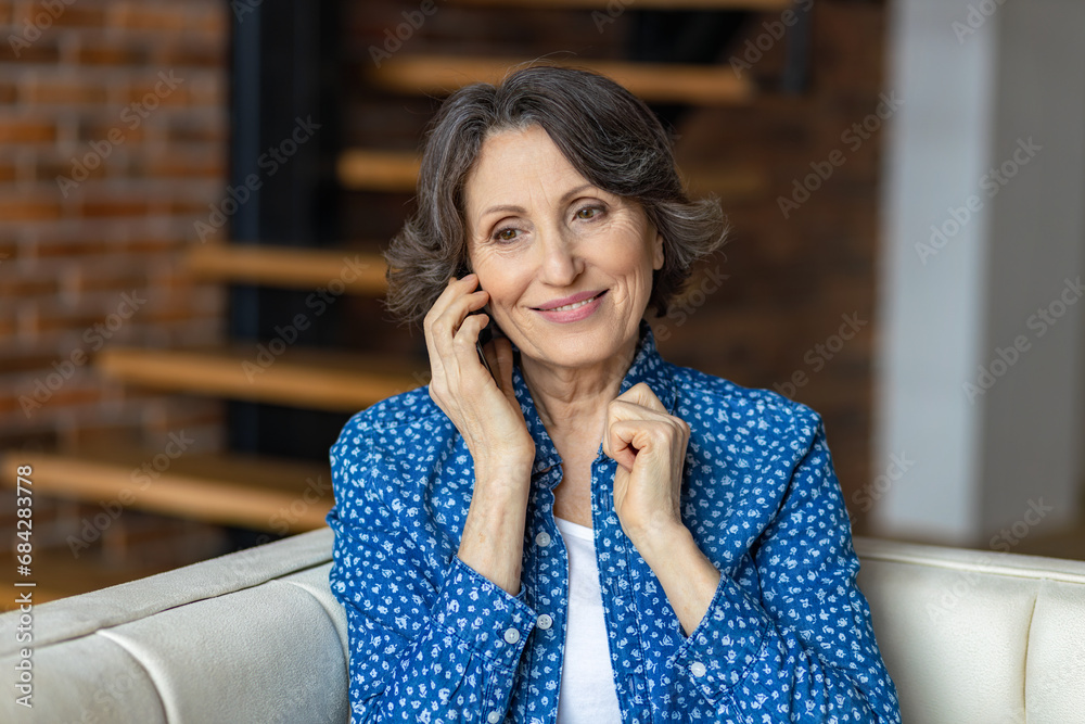 Happy smiling senior woman calling on mobile phone sitting at home on the couch Happy smiling senior woman calling on mobile phone sitting at home on the couch
