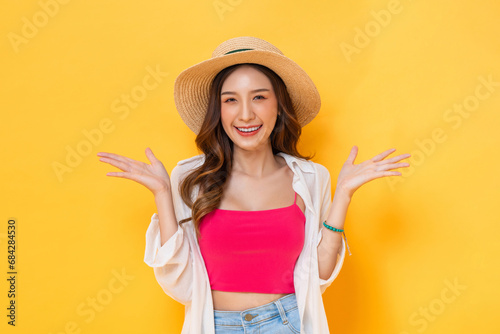 Waist up portrait of smiling pretty Asian woman in summer outfit with open hand gesture in colorful yellow isolated background studio shot photo