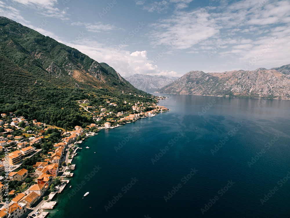 Red roofs of houses with private piers on the shores of the Bay of Kotor. Dobrota, Montenegro. Drone