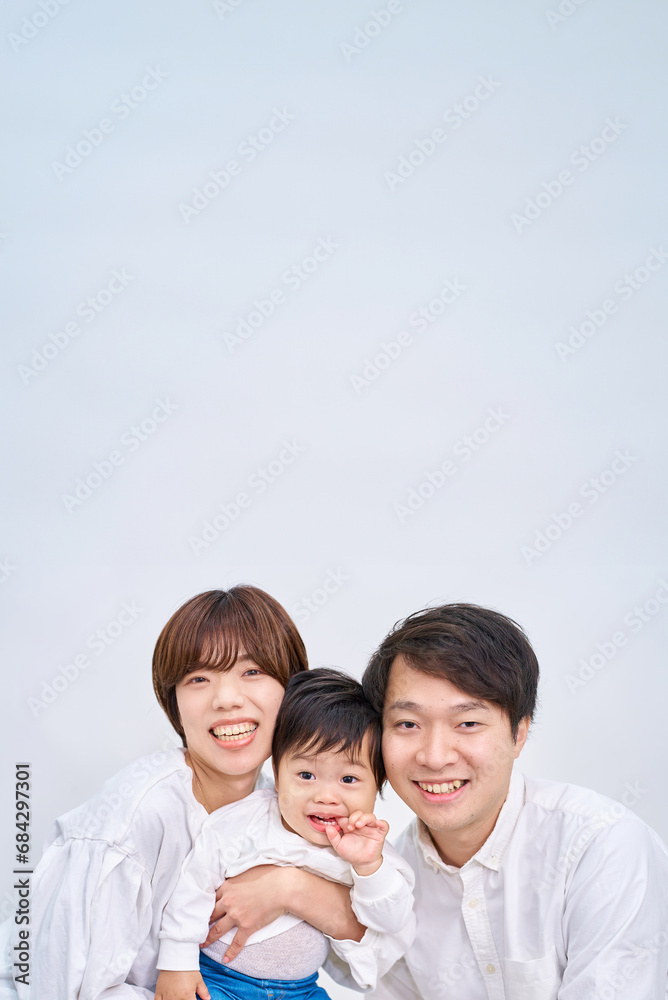 白い背景の前に笑顔で並ぶ家族