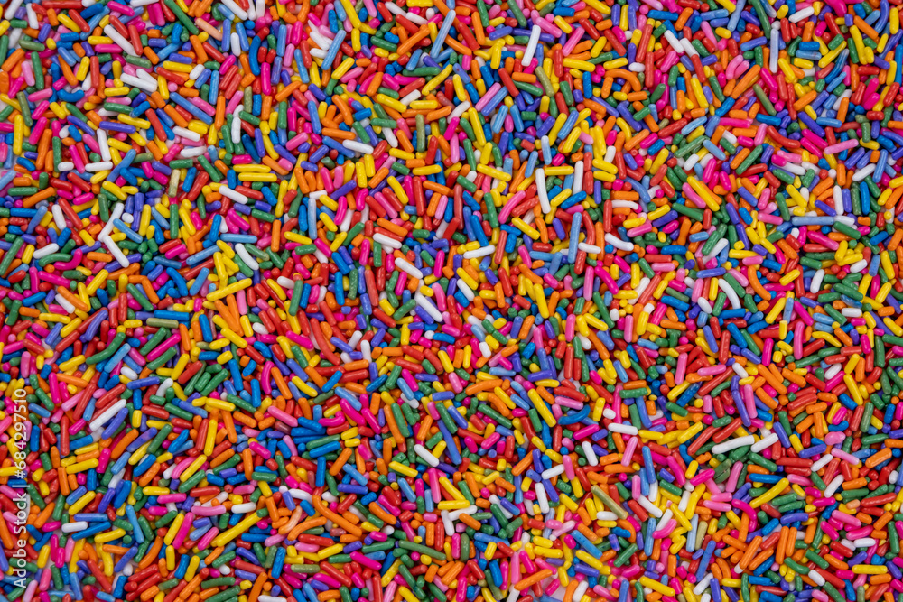 background of multi-colored sprinkles for sweets and multi-colored dragees or sweets. The concept of celebrating a birthday, party or other holidays. trendy, sweet background