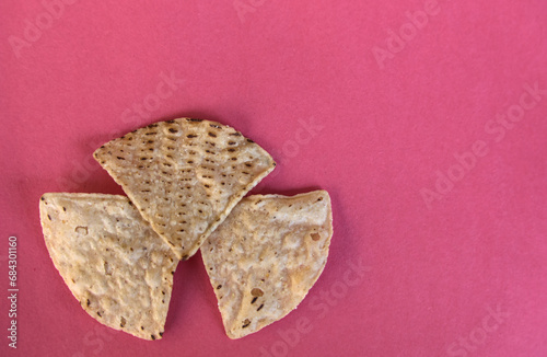 corn tortilla chips isolated on a pink red background (cut out masa chip for dipping) restaurant style crunchy toasted yellow, white nixtamalized hominy (mexican food, totopos) photo