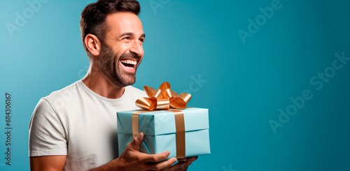 hombre feliz y sonriente entregando una caja de regalo de cumpleaños aislado en un fondo azul 