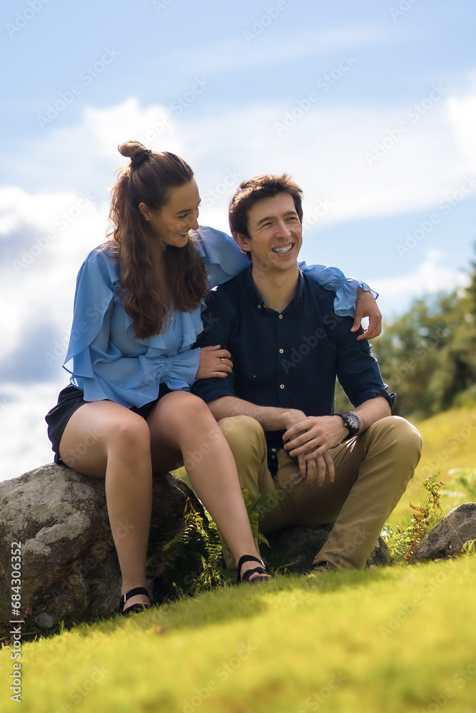 Young stylish couple embracing sitting on the mountain