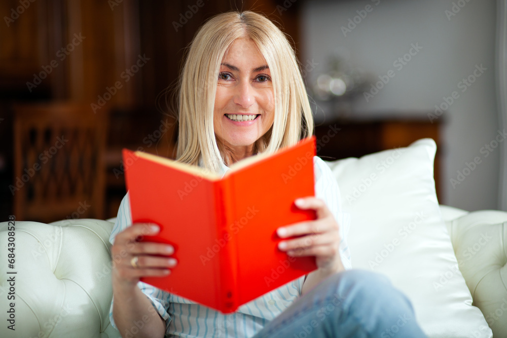 Mature woman reading a book at home on her couch Mature woman reading a book at home on her couch