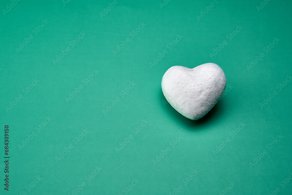 Fototapeta premium White heart representing the purity of love on a green background.