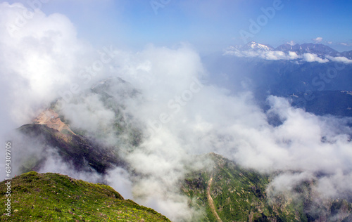 Dramatic landscape with mountain tops and white clouds against a blue sky background and space to copy