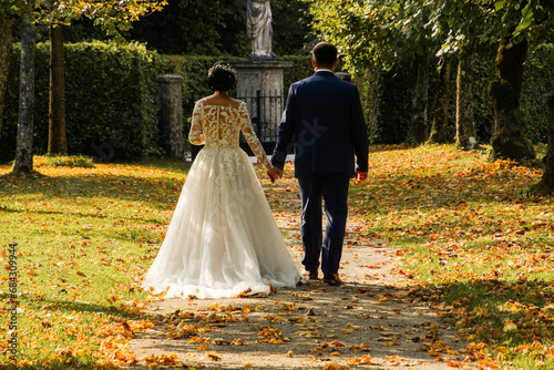 bride and groom walking in park in autumn