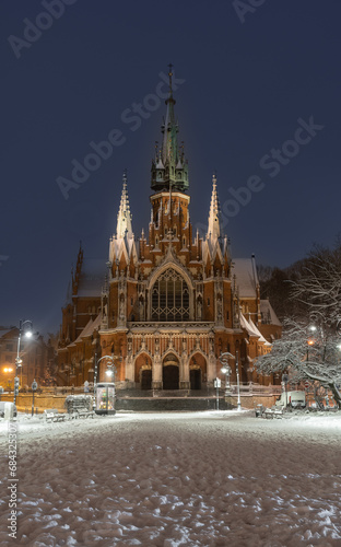 Picturesque gothic revival St Joseph church on Podgorski square during snowy night, Krakow, Poland
