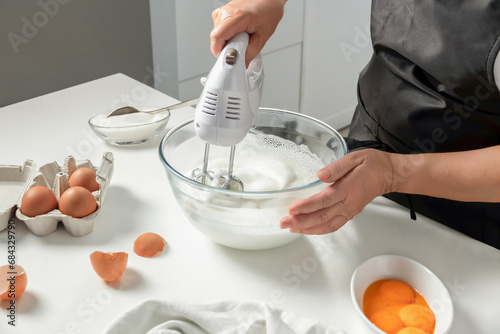 A female hands beat egg whites with a mixer photo