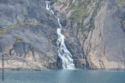 Waterfalls are plentiful in Prince Christian Sound as glaciers melt into the sea, Greenland.
