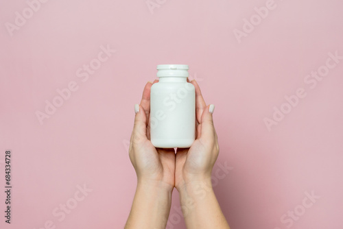 Bottle of pills or vitamins in woman's hand. Product branding mockup.